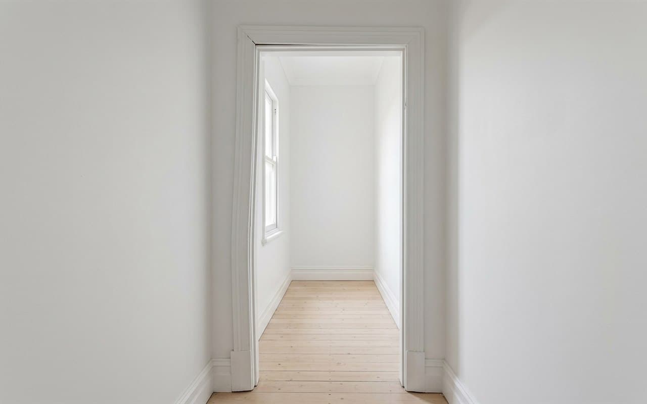 A doorway in a white room, seen straight on, with a pale timber floor beyond it.