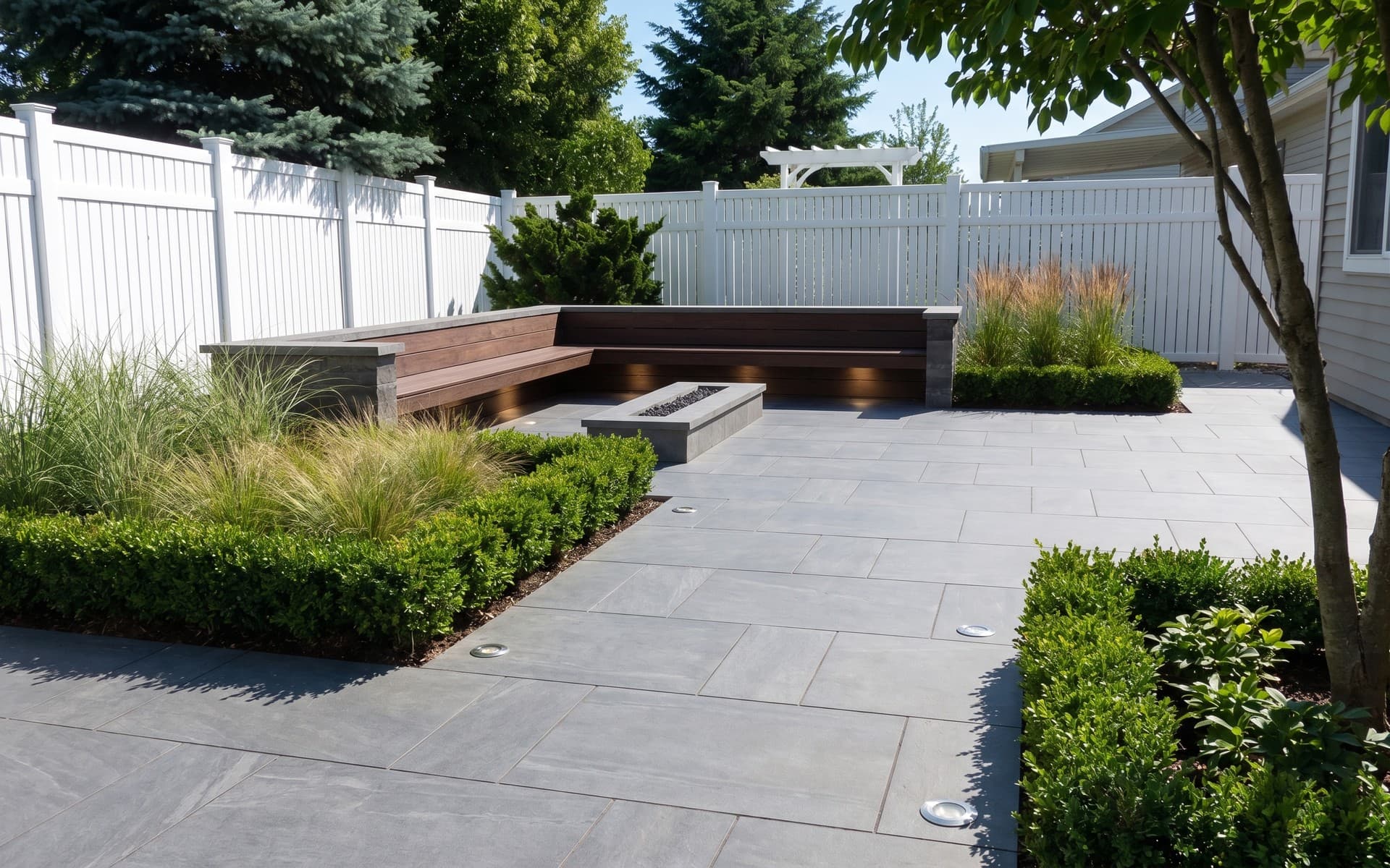 The same backyard redesigned by AI with gray paving, a built-in bench, low hedges and grasses where the lawn was.
